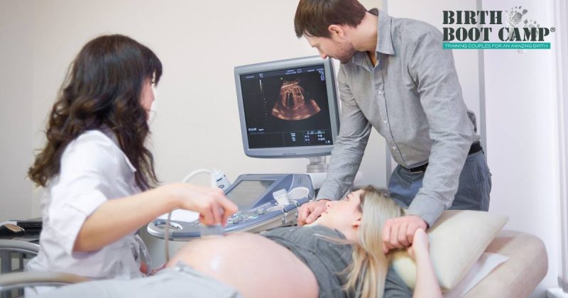 Pregnant woman and her partner at the Dr. office taking an ultrasound image of their baby. Logo-Birth Boot Camp